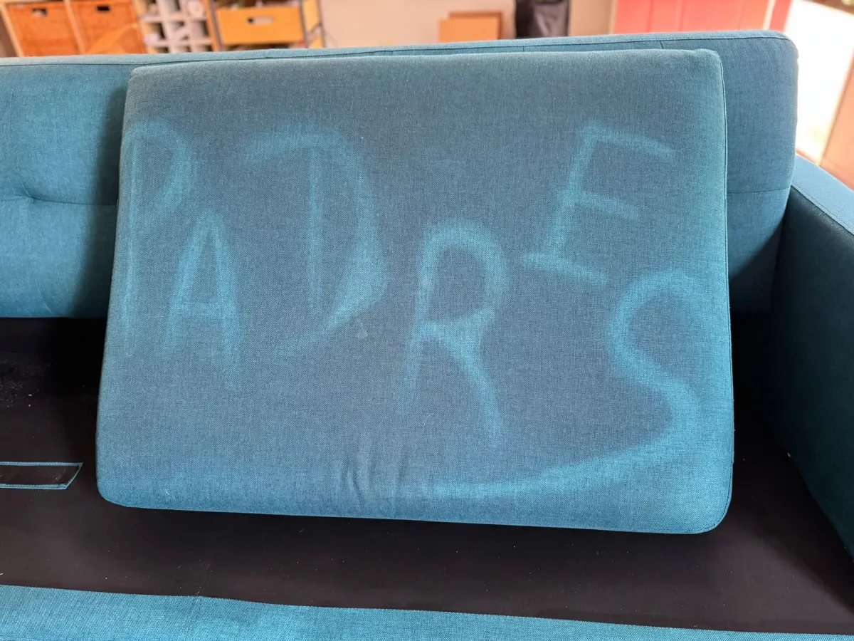 βPADRESβ written on a sofa cushion by cleaning, showing hidden soil βPADRESβ written on a sofa cushion by cleaning, showing hidden soil