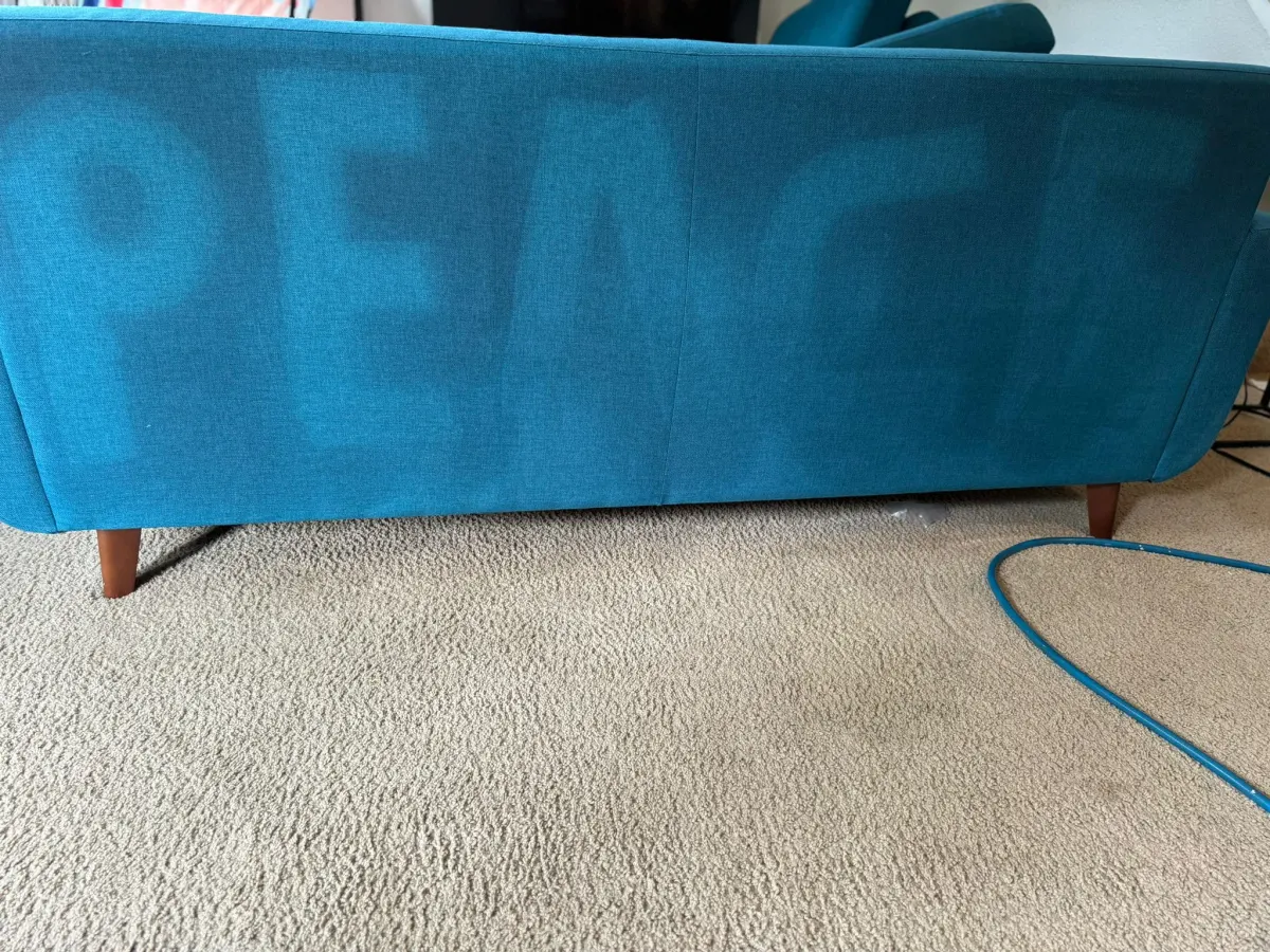 βPEACEβ cleaned into the back of a teal sofa βPEACEβ cleaned into the back of a teal sofa